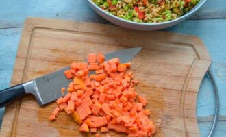 Нарезанная кубиками папайя на разделочной доске рядом с миской с салатом из брокколи, яблок и перца