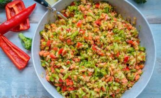 Готовый салат из брокколи с яблоками, сладким перцем и грецкими орехами в глубокой миске на столе