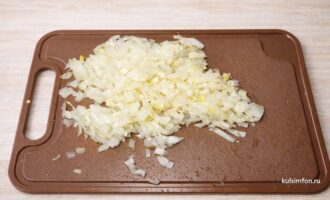 Мелко нарезанный репчатый лук на разделочной доске