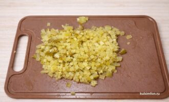 Мелко нарезанные маринованные огурцы на разделочной доске