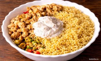 Лапша и обжаренная курица с добавлением майонеза и специй в салатнике