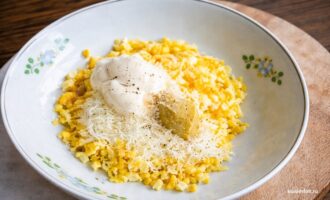 Измельченные вареные яйца с майонезом и тертым сыром в миске