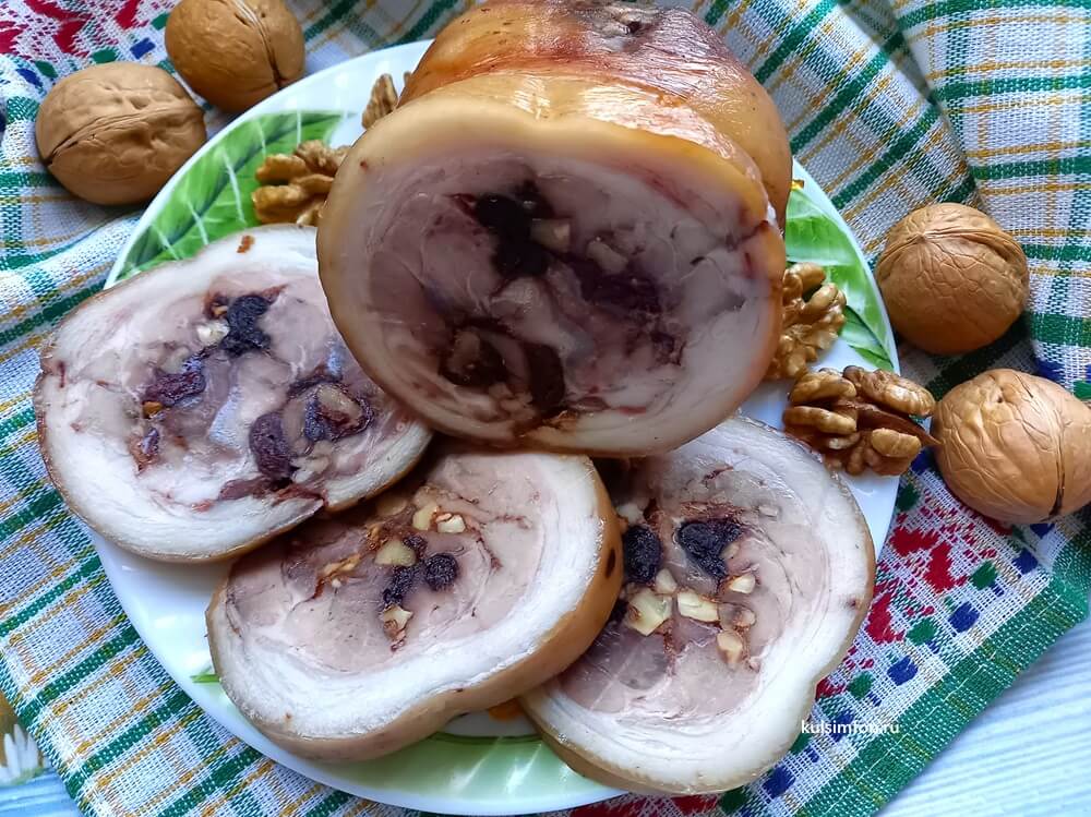 Рулет из свиной рульки вареный с черносливом и орехами на тарелке
