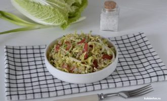 Готовый салат с пекинской капустой, киноа и овощами в тарелке, поданный на столе с салфеткой и вилкой