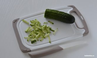 Нарезанный соломкой свежий огурец на разделочной доске с ножом