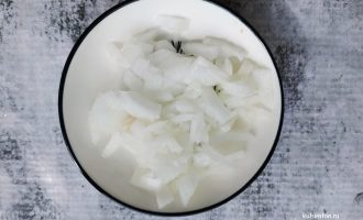 Мелко нарезанный репчатый лук на разделочной доске