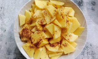 Тонко нарезанный картофель в миске со специями и солью