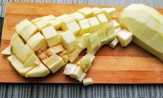 Нарезанные кубиками баклажаны на разделочной доске