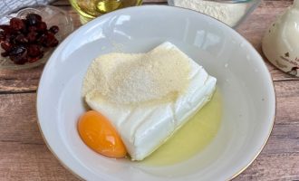 Творог, яйцо, манка и сахар в глубокой миске перед замешиванием