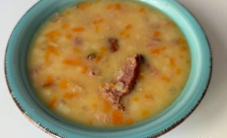 Готовый гороховый суп с копчеными ребрами и картофелем, подача с зеленью