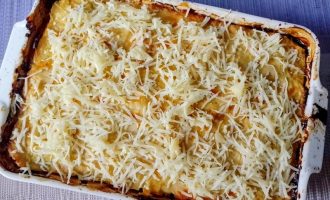 Готовая капустная запеканка с куриной грудкой, посыпанная сыром и запеченная до румяной корочки