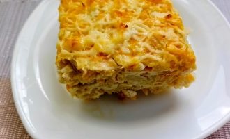Кусочек готовой капустной запеканки с куриной грудкой и сыром на тарелке