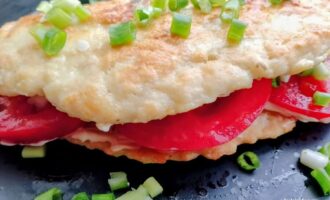 Готовый куриный блинчик с творожным сыром и помидорами, поданный на тарелке.