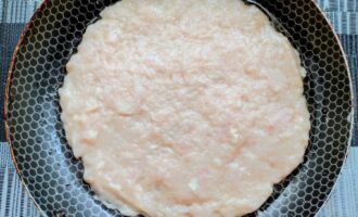 Куриный фарш на сковороде, распределенный в форме блинчика.