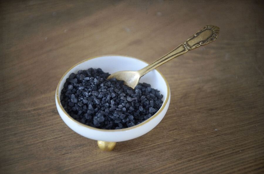 Черная лавовая соль крупного помола в белой пиале с золотой ложкой