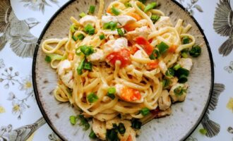 Готовые спагетти с куриной грудкой в сливочно-сырном соусе, поданные на тарелке