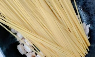 Спагетти, выложенные в глубокую сковороду перед тушением