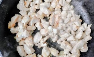 Кусочки куриной грудки, обжаривающиеся с луком