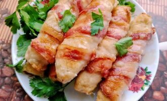 Готовые куриные колбаски с сыром в беконе, поданные со свежей зеленью