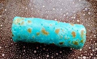 Голубой блинчик с яблоком свернутый рулетом