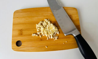 Мелко нарезанный чеснок на разделочной доске