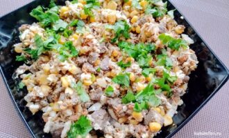 Салат с куриной печенью и кукурузой с зеленью на тарелке