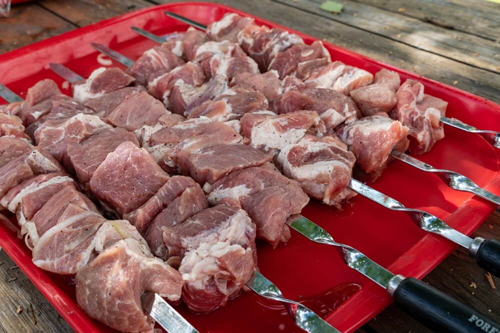 Кусочки свинины для шашлыка нанизаны на шампуры